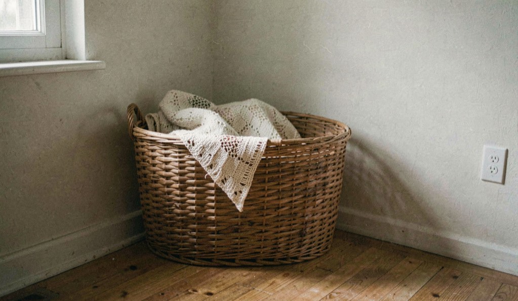 Un panier épais est placé dans un angle tranquille du salon, légèrement éloigné du passage, avec une couverture et une lumière douce.